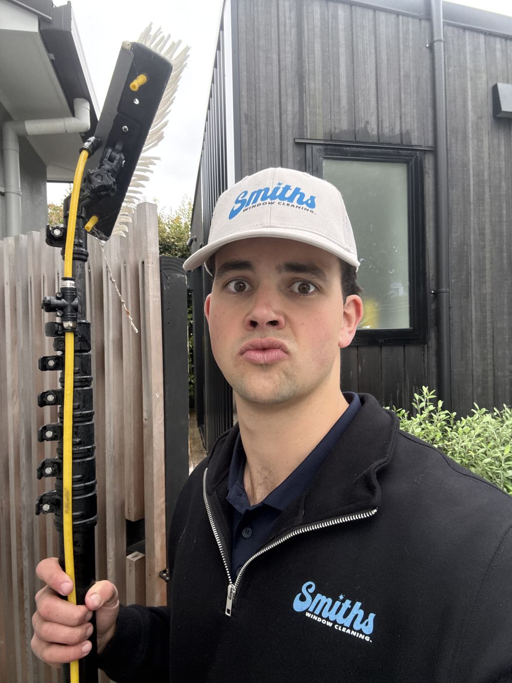Ashton Smith, founder of Smith's Window Cleaning, holding a water-fed pole on the job